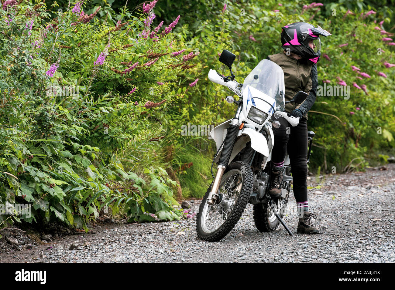 A women takes a break from motorcycle riding and stands with her bike. Stock Photo