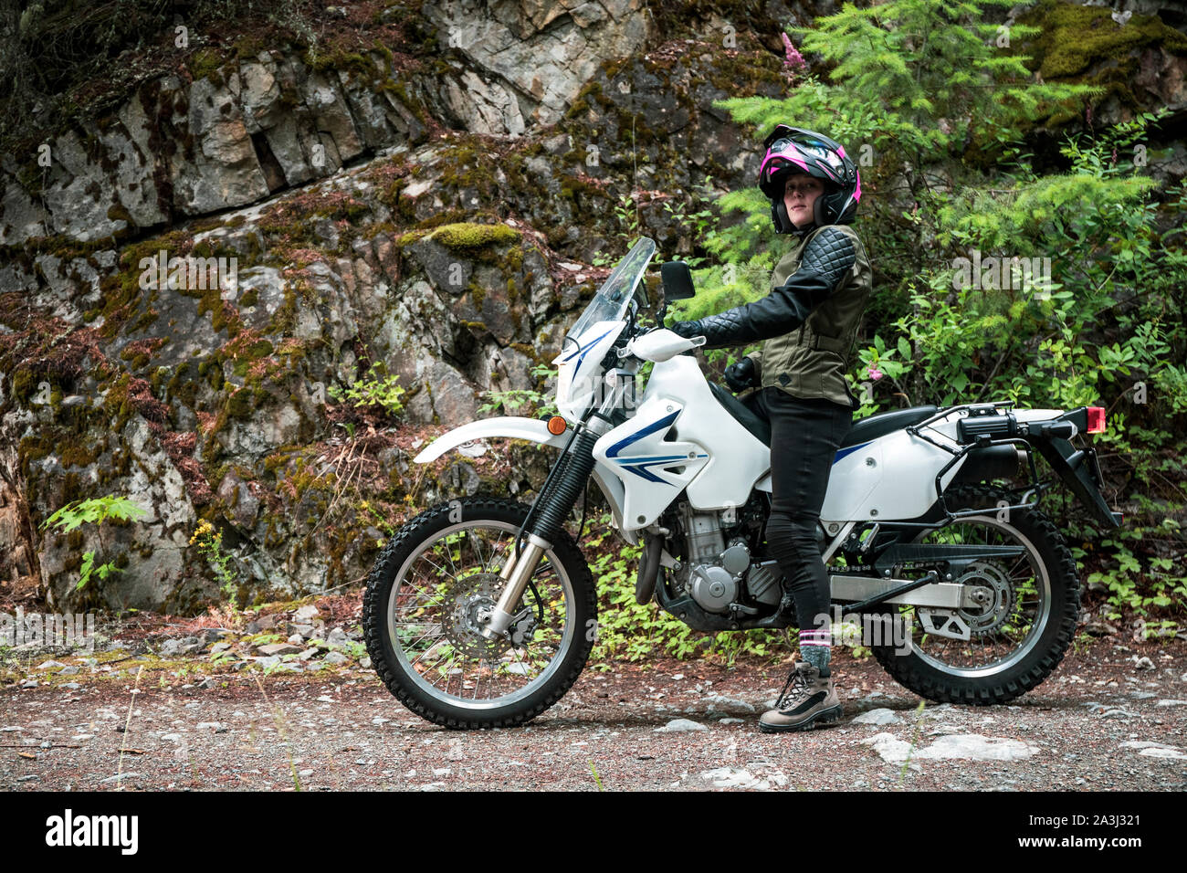 A women riding a motorcycling stops on a gravel road. Stock Photo