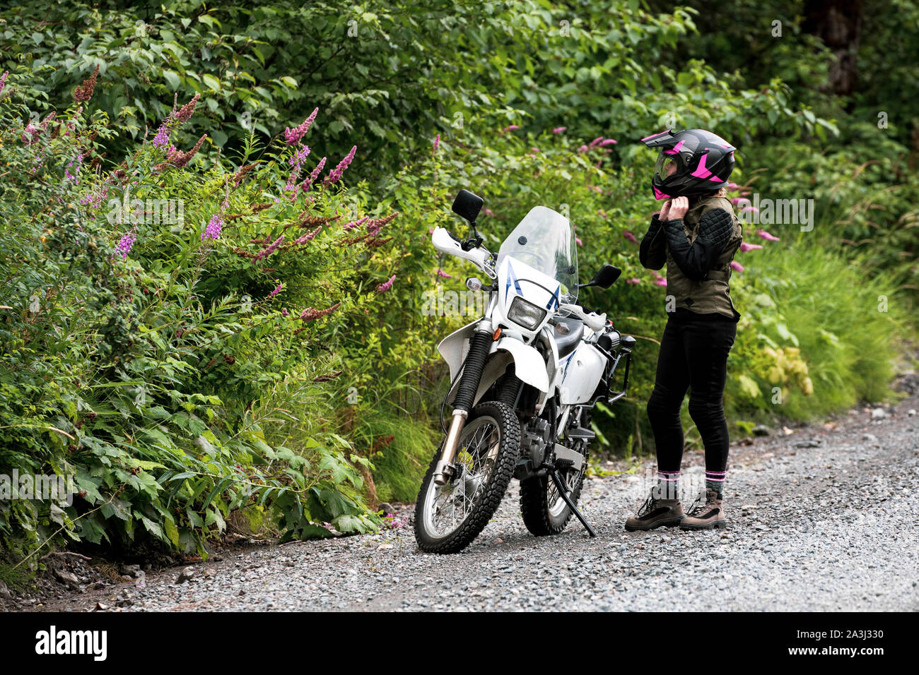 A women takes a break from motorcycle riding and takes off her helmet. Stock Photo