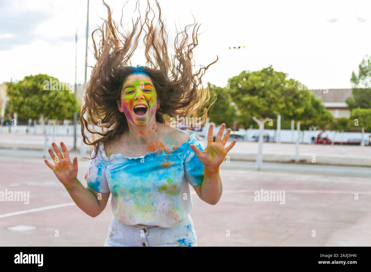 teenage girl jumps and screams for joy, playing with colored powders a Stock Photo