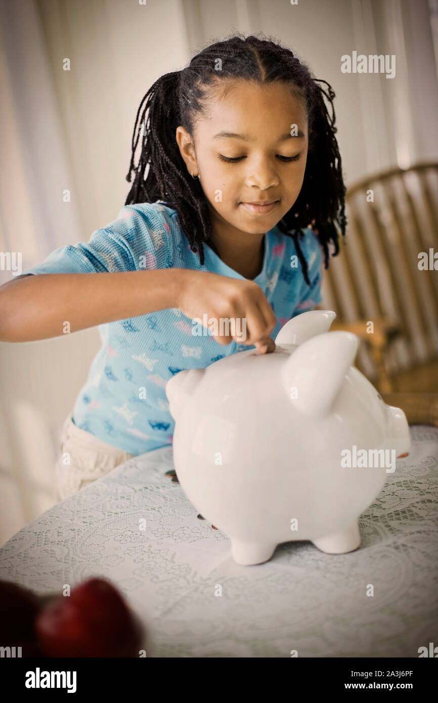 Girl putting money into a piggy bank Stock Photo - Alamy