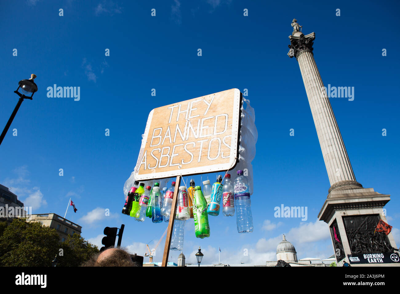 London, UK. 08th Oct, 2019. Placard saying, they banned asbestos, during the environmental protest by Extinction Rebellion activist group.Extinction Rebellion is an international movement that uses non-violent civil disobedience in an attempt to halt mass extinction and minimise the risk of social collapse. The group has blocked a number of key junctions in central London. Credit: SOPA Images Limited/Alamy Live News Stock Photo