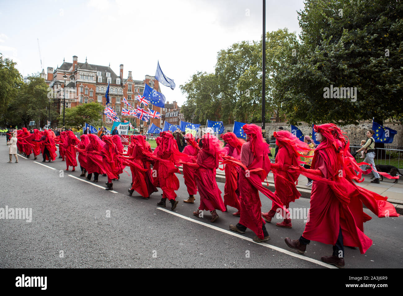 London, UK. 08th Oct, 2019. Environmentalist performance art troupe the 'Red Rebel Brigade' walk silently close to parliament during the environmental protest by Extinction Rebellion activist group.Extinction Rebellion is an international movement that uses non-violent civil disobedience in an attempt to halt mass extinction and minimise the risk of social collapse. The group has blocked a number of key junctions in central London. Credit: SOPA Images Limited/Alamy Live News Stock Photo