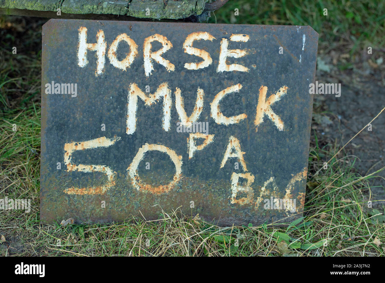 “Horse Muck”, hand painted onto a corroded metal sheet, and left by a Norfolk farm gate entrance. Manure for the roadside purchase, by passersby. Stock Photo