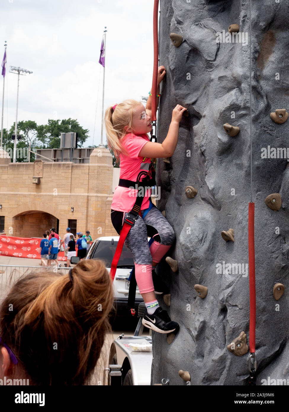 Young girl age 9 scaling climbing wall wearing harness and safety straps at  St Thomas University Special Olympic event. St Paul Minnesota MN USA Stock  Photo - Alamy