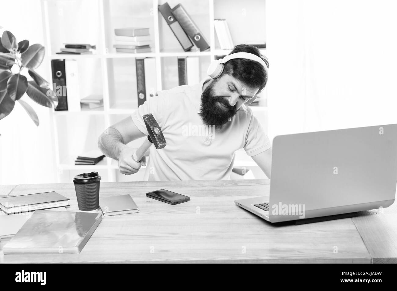 Man bearded guy headphones office swing hammer on smartphone. Spoiled communication. Failed mobile negotiations. Most annoying thing about work in call center. Incoming call. Annoying client calling. Stock Photo