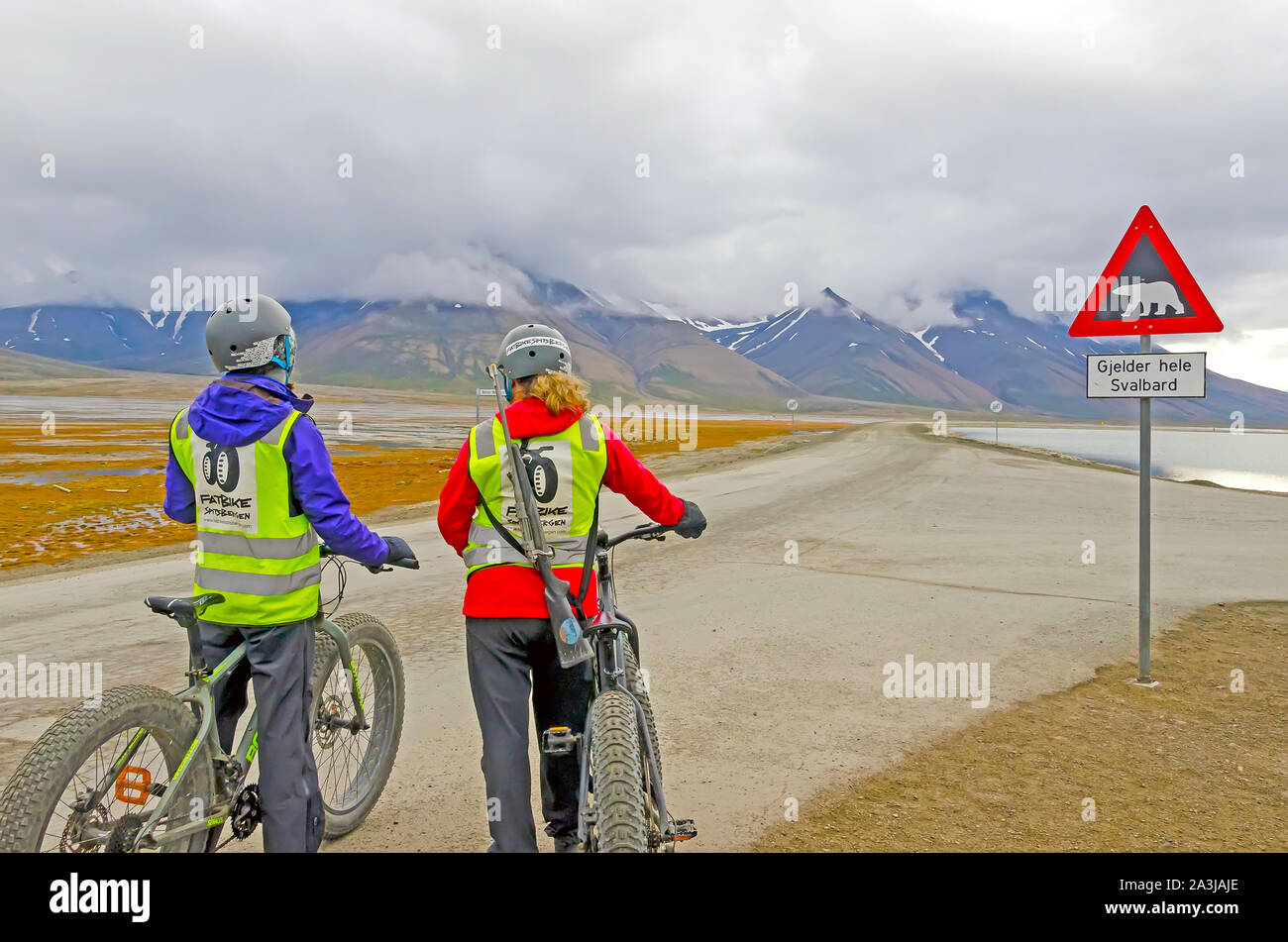 Woman on Bicycle Carries  Polar  Bear Rifle, Longyearbyen, Svalbard, Norway Stock Photo