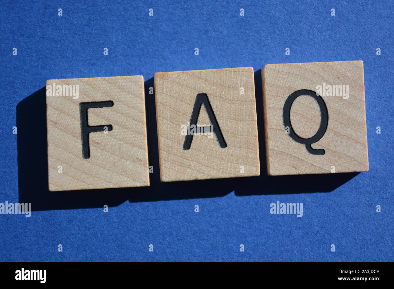 FAQ acronym for Frequently Asked Questions in 3d wooden alphabet letters isolated on a blue