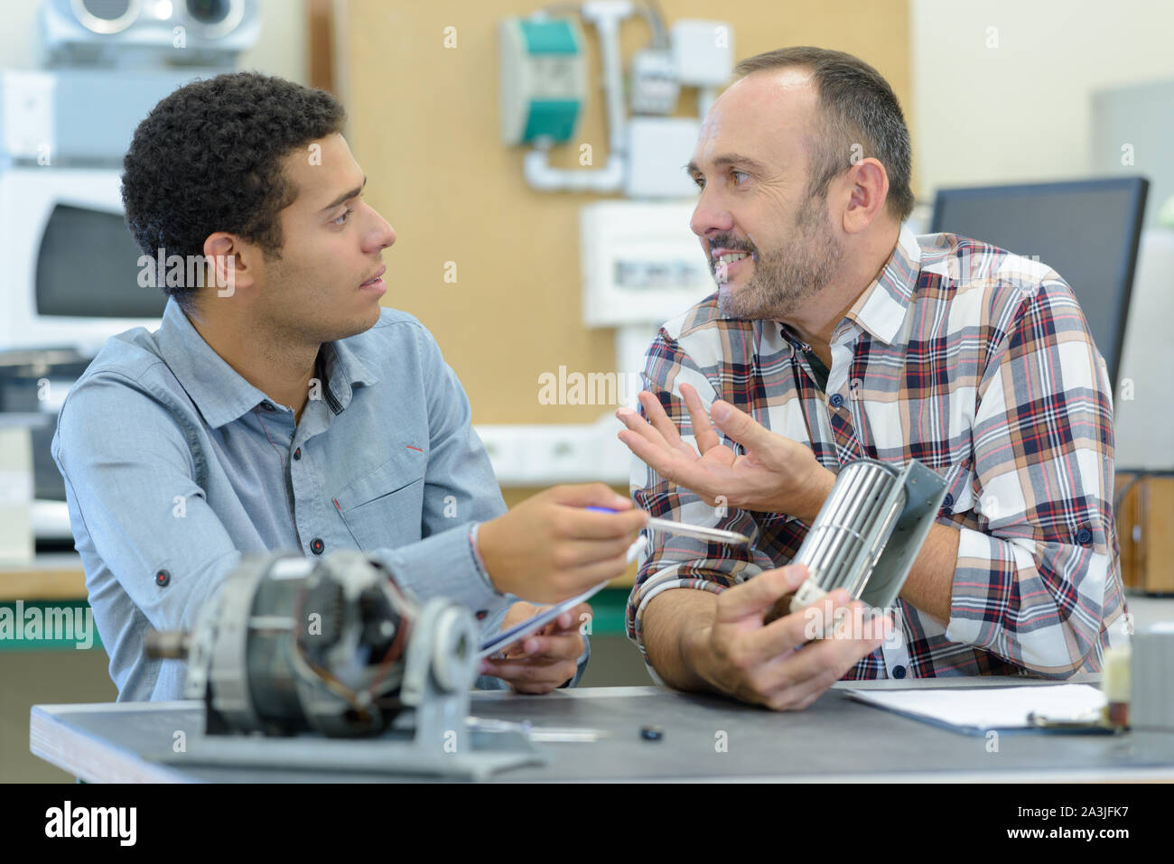 engineer and apprentice examining component in office Stock Photo