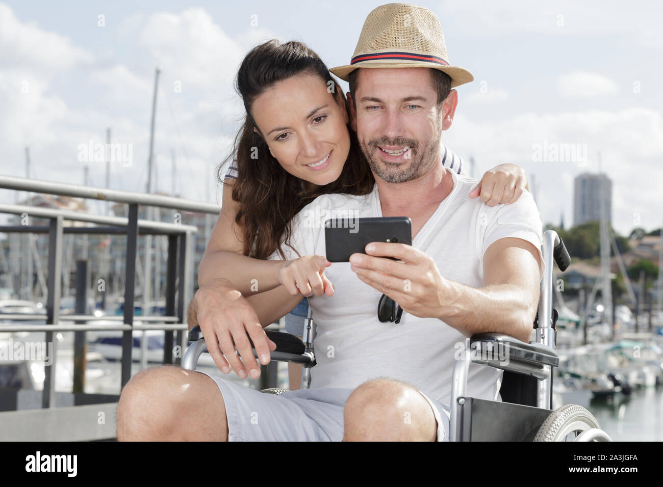 couple taking selfie by harbour man in wheelchair Stock Photo - Alamy