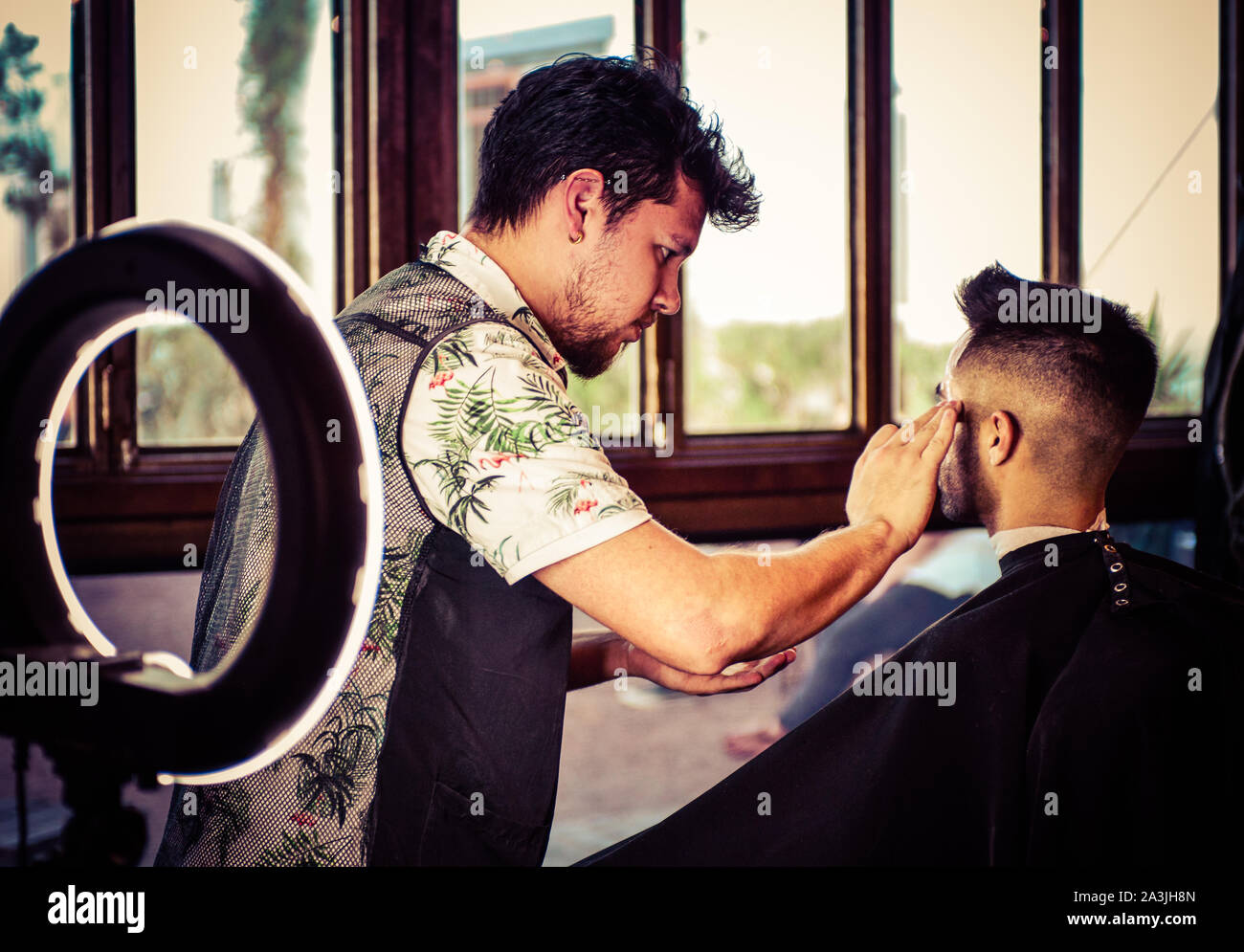 After a new haircut, barber preps a client for a shave with the help of