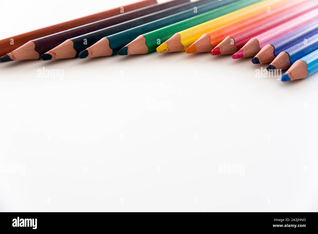 Close up of a number of colorful, thick crayons arranged to form  an arch on white neutral background, with large copy space. Stock Photo