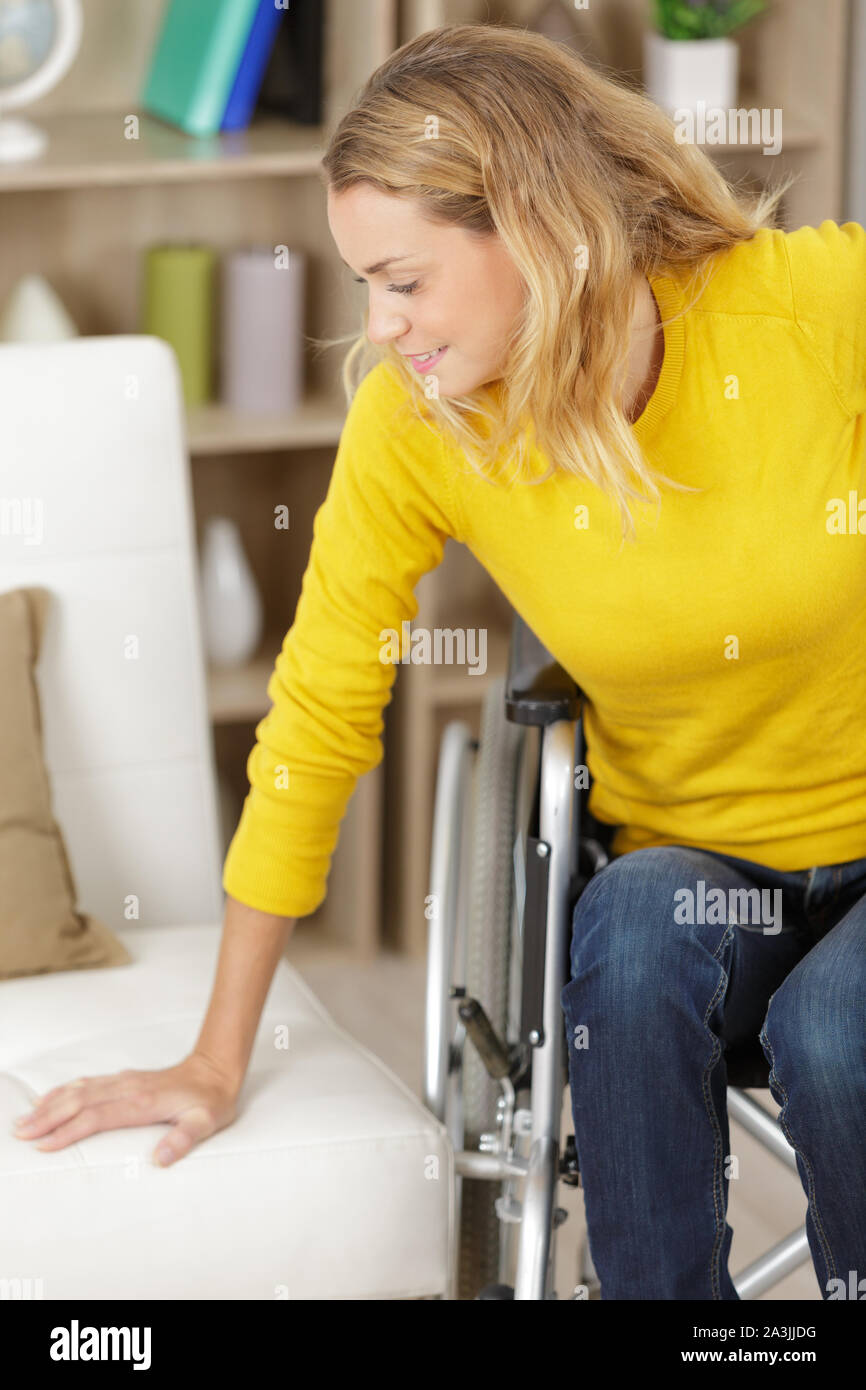 woman transferring herself from the wheelchair to the sofa Stock Photo