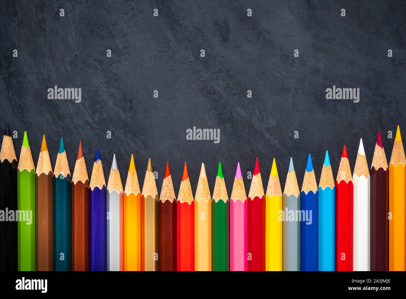 Colored pencils on chalkboard background. Top view and copy space