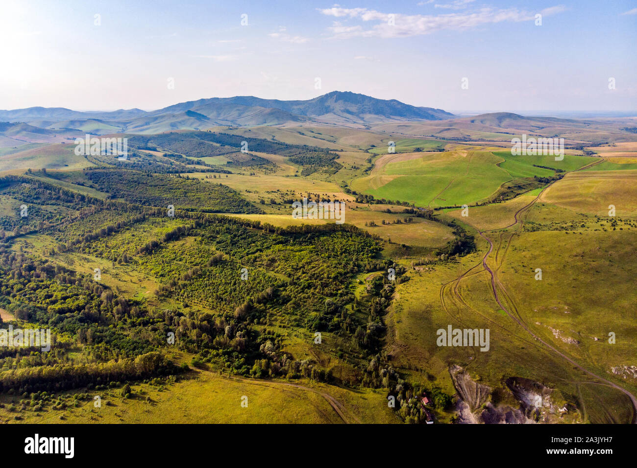 Autumn view. Hilly terrain. Yellow slopes and trees contrast with green fields. Top view of the field in Altai. Stock Photo