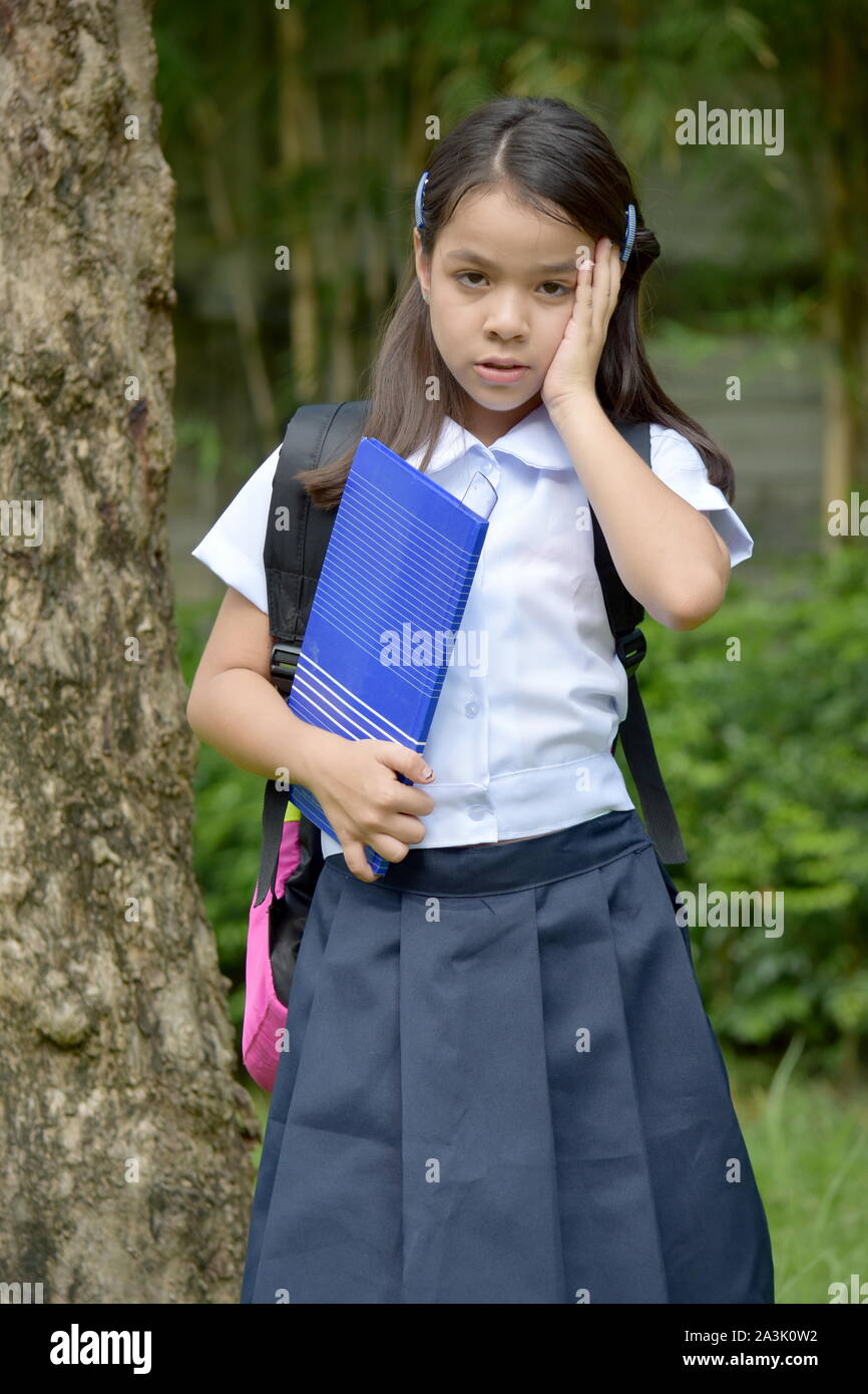 Forgetful Young Minority Girl Student Wearing Uniform With Books Stock Photo