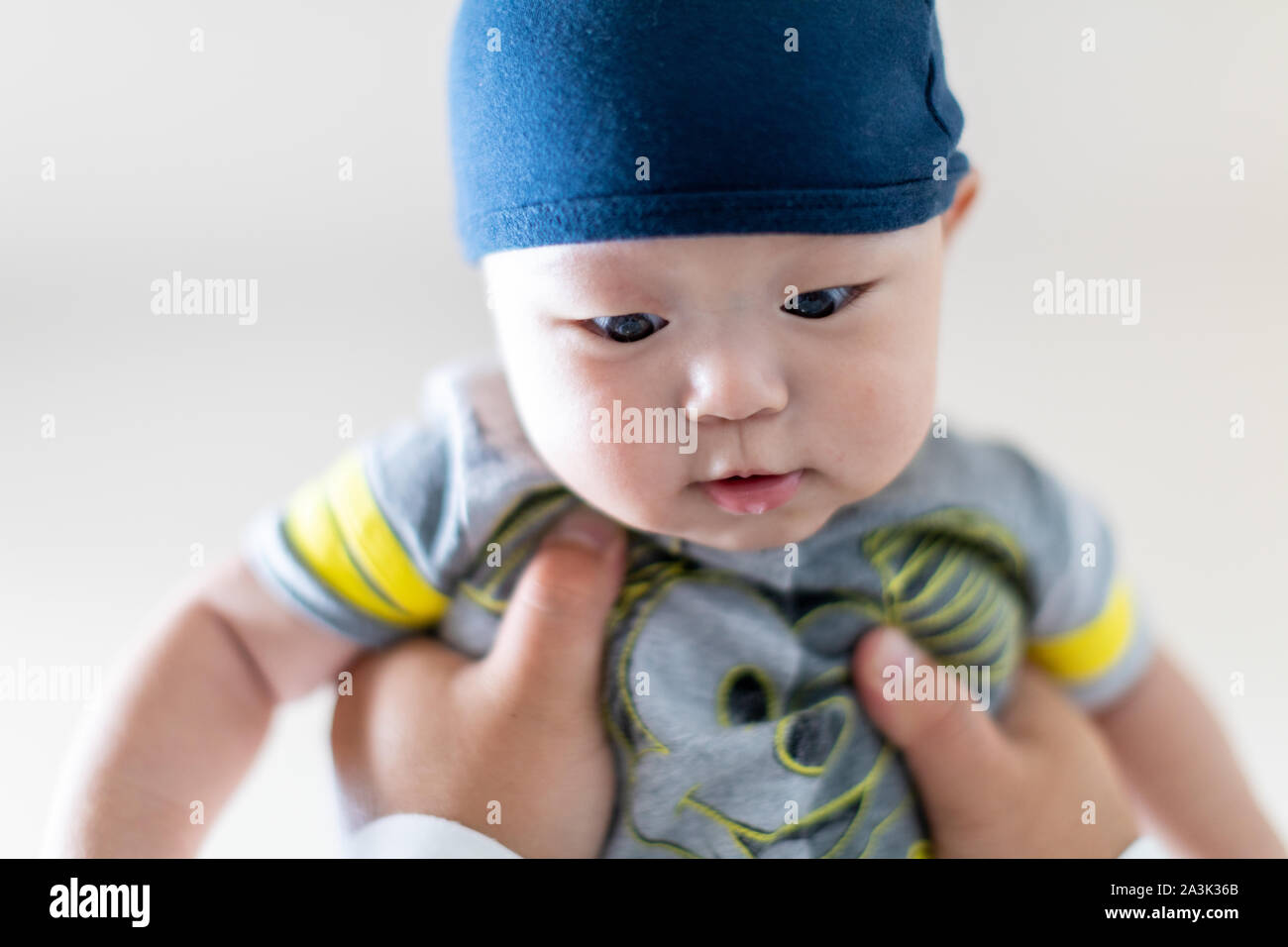 Cute baby boy wearing blue hat having a play time with his father Stock