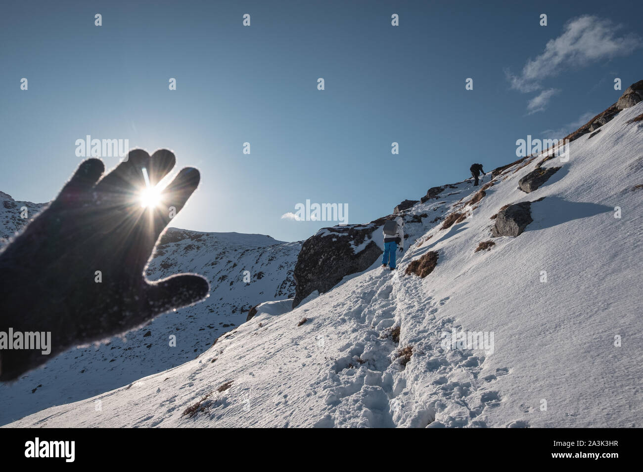 Hand wearing glove covering on the sunstars at mountain summit Stock Photo