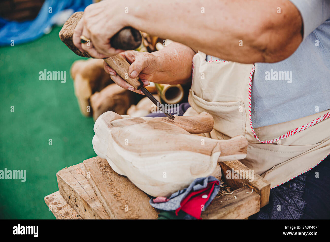 Skilful Thai art craft carpenter using hammer to chisel a wooden elephant handmade woodcraft OTOP products Stock Photo