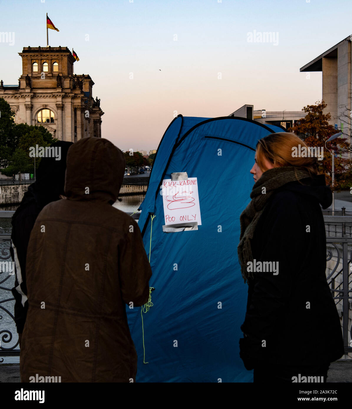 Berlin, Germany. 09th Oct, 2019. Demonstrators stand in front of a mobile toilet cabin with the inscription 'Kack-Kabine Poo only' on the Marschallbrücke bridge. This was occupied early in the morning by about 300 activists of the environmental movement Extinction Rebellion. Credit: Paul Zinken/dpa/Alamy Live News Stock Photo