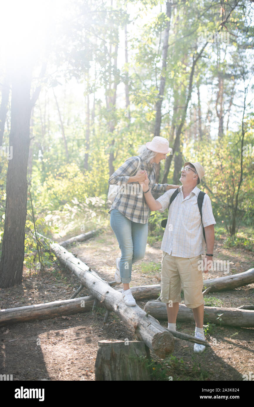 Loving husband supporting his wife standing on the tree roots Stock Photo