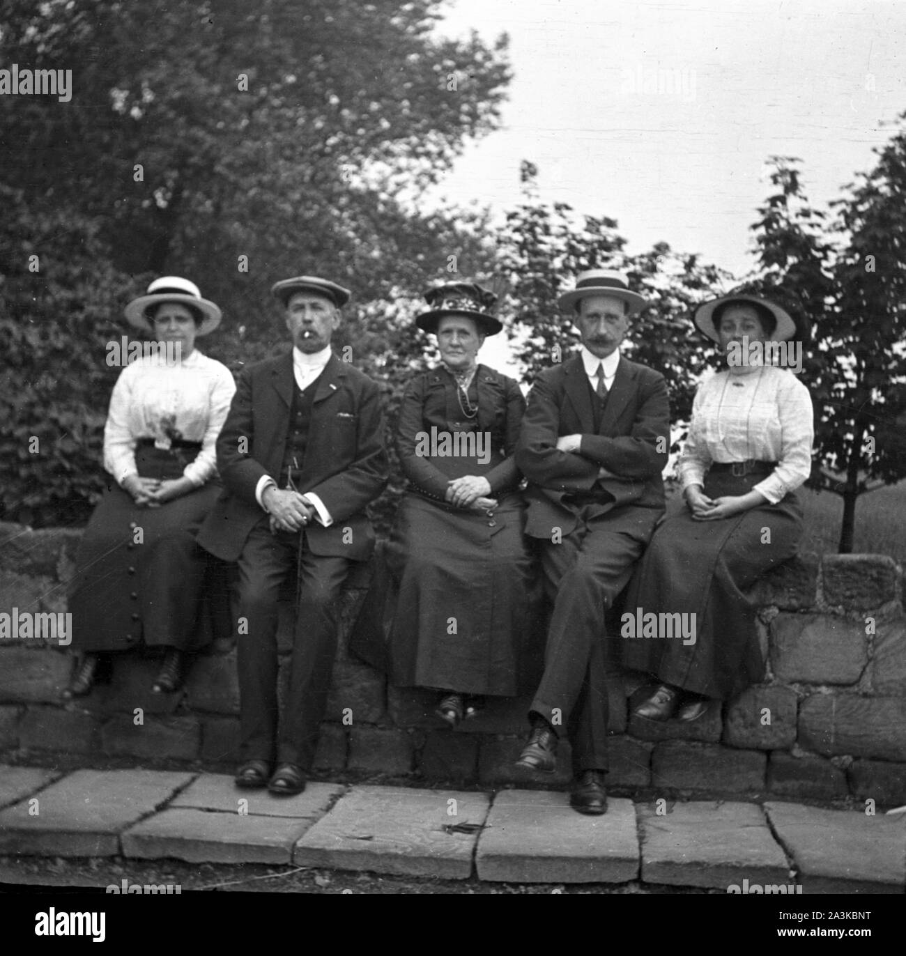 A group of 5 people sitting on a bridge before the second image peering over the bridge  from behind c1910. An early photographic attempt at humour. 1st of 2 photographs. Photo by Tony Henshaw Archive Stock Photo
