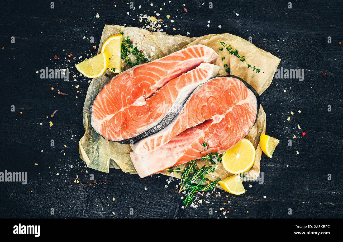 Salmon steaks on black wooden background, red fish, top view, photo filtered in vintage style Stock Photo