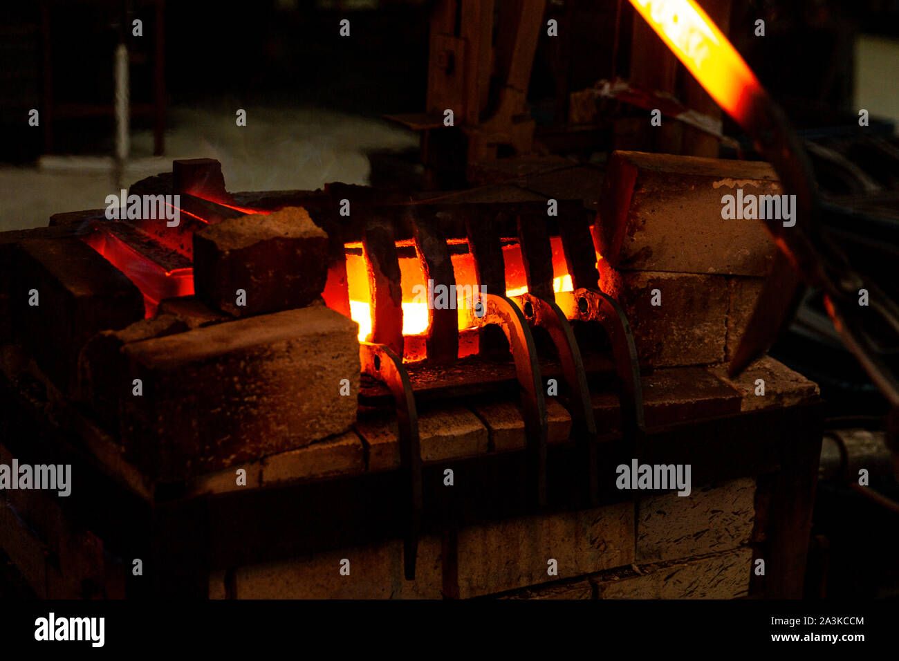 Blacksmith heating metal bars in industrial furnace Stock Photo Alamy