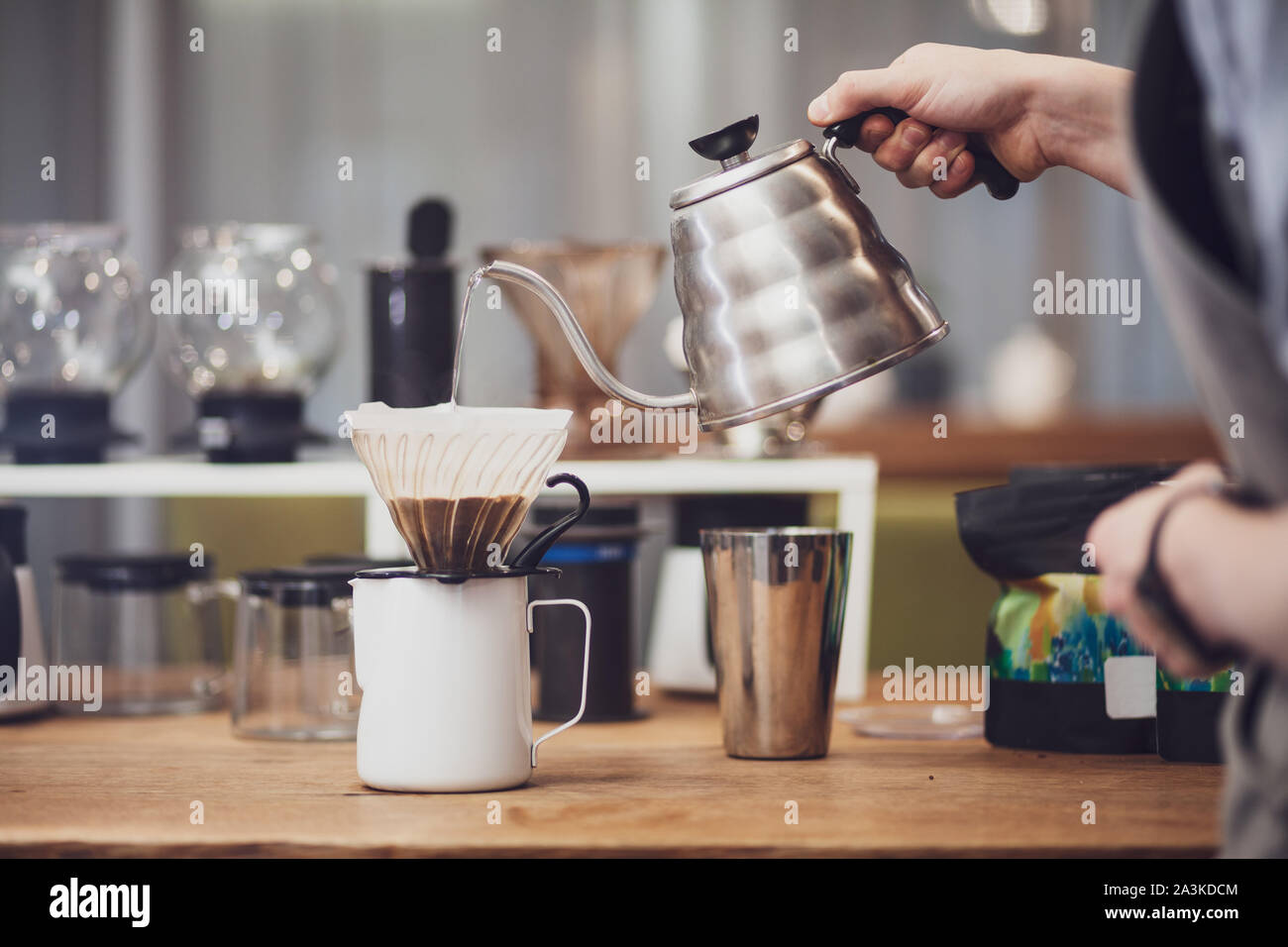 Barista pours over coffee in funnel. Barista's hand hold metal kettle with boiling water Stock Photo