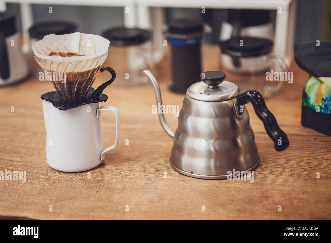 Alternative coffee. Funnel with filter and coffee over the pitcher and  metal kettle Stock Photo - Alamy