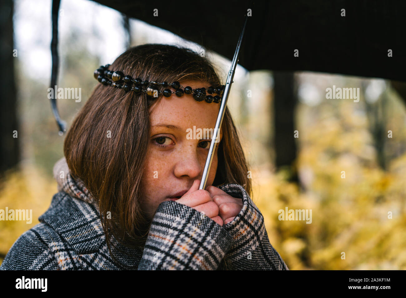 Red-headed freckled girl in autumn yellow park under the umbrella. Stock Photo
