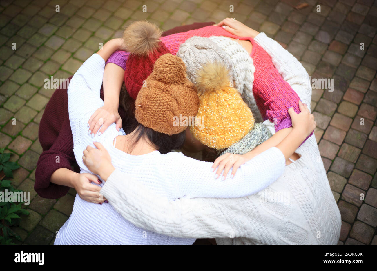 Girls in warm knitted clothes and hats hug, top view. Autumn day, a group of friends. Positive emotions. Stock Photo
