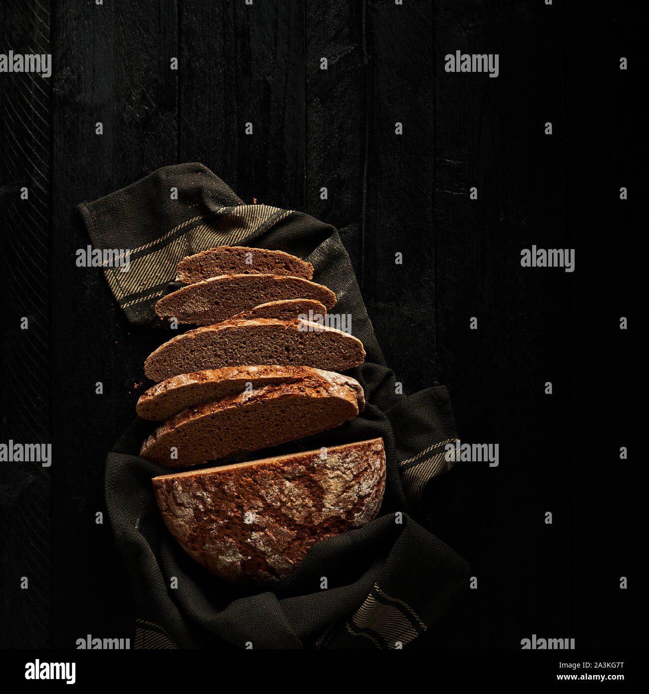 Sliced bread on black wooden background. Top view. Copy space. Square crop. Stock Photo