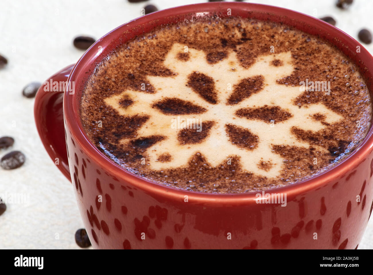 A cappuccino with chocolate snowflake motif, snowy background and scattering of coffee beans sets the scene for a festive Christmas heartwarming drink Stock Photo