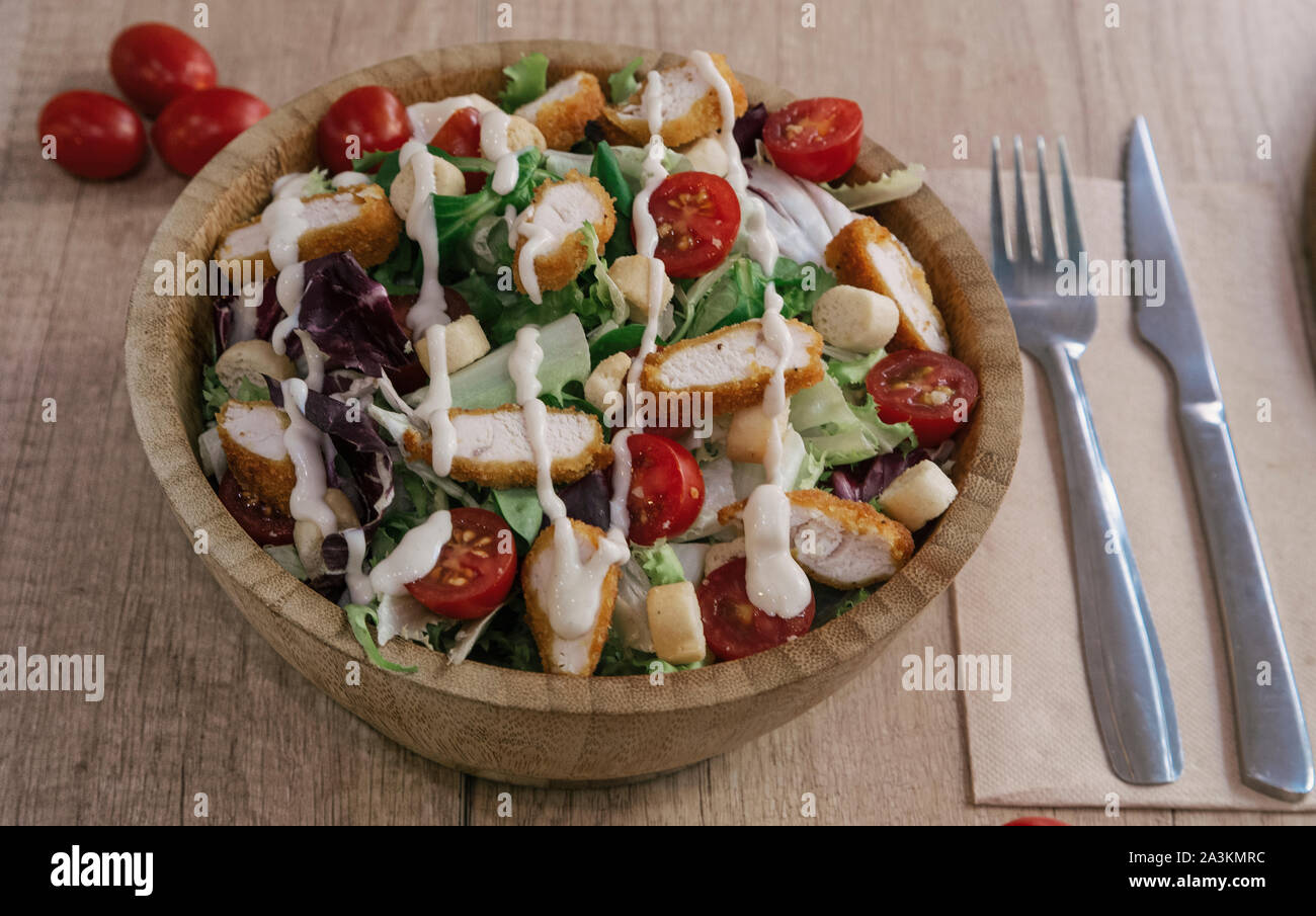Organic caesar salad in wooden bowl with caesar dressing. International