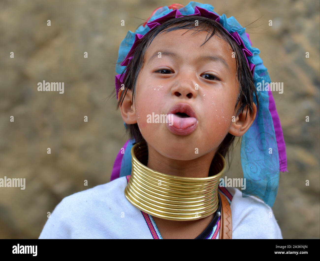 Little Myanmarese Kayan Lahwi girl with tribal brass neck rings/coils sticks out her tongue. Stock Photo