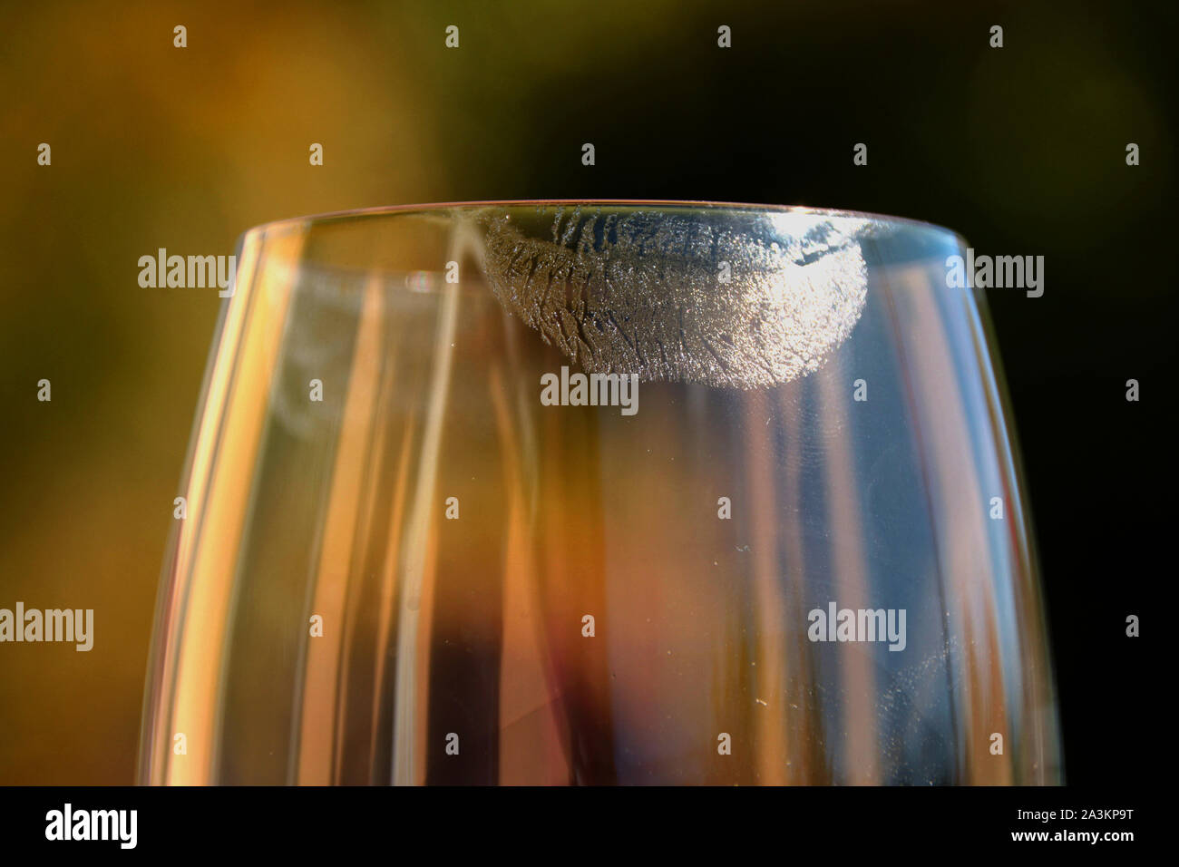 closeup of transparent lipstick imprints on wine glass in front of