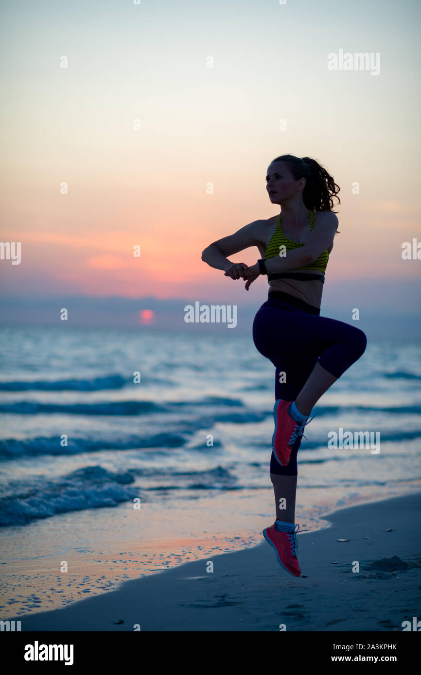 Full length portrait of fit woman in fitness clothes on the beach in ...