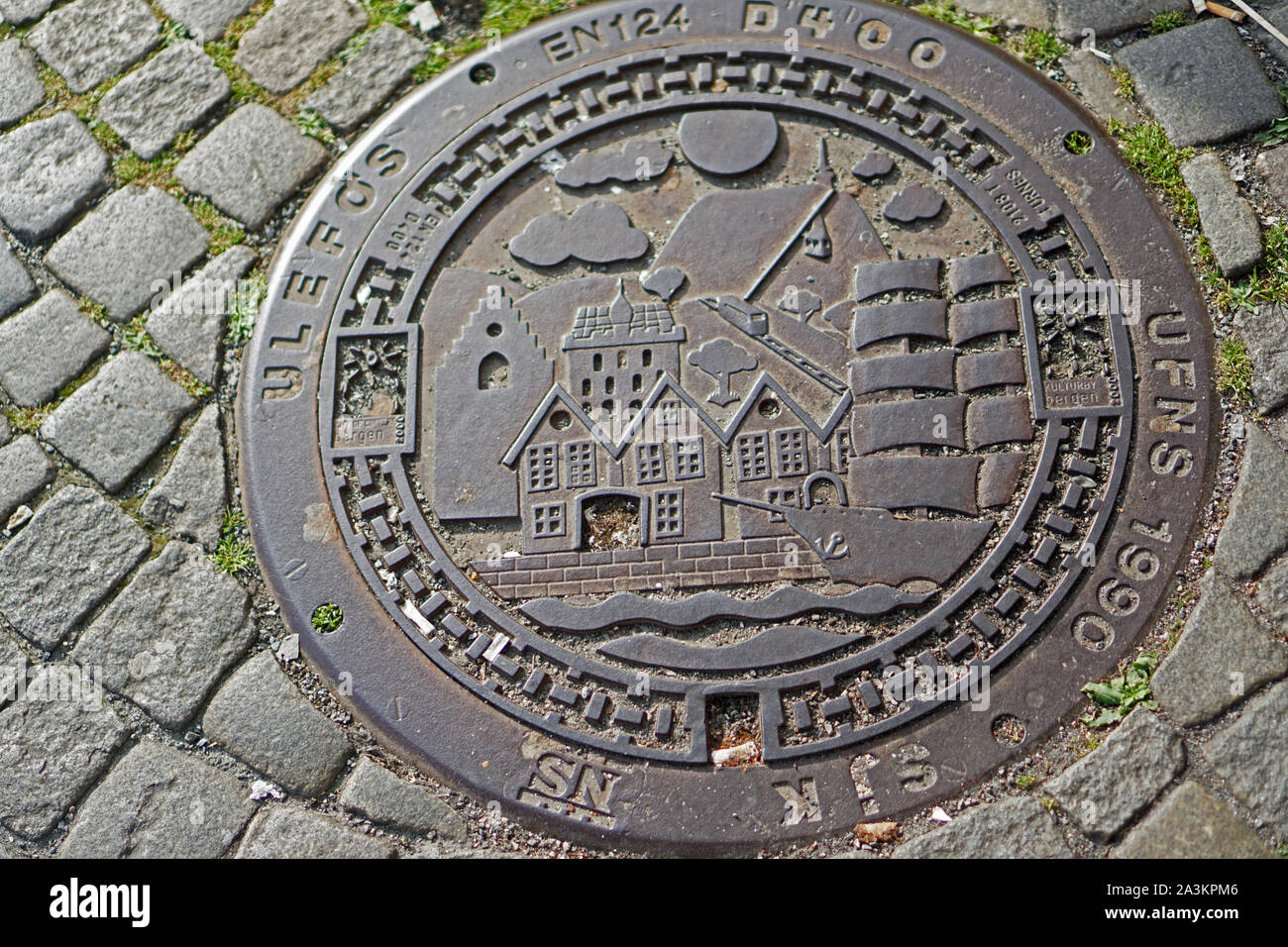 An iron-cast on the floor of a street in Bryggen, Bergen, Norway showing a viking ship and Bryggen houses Stock Photo