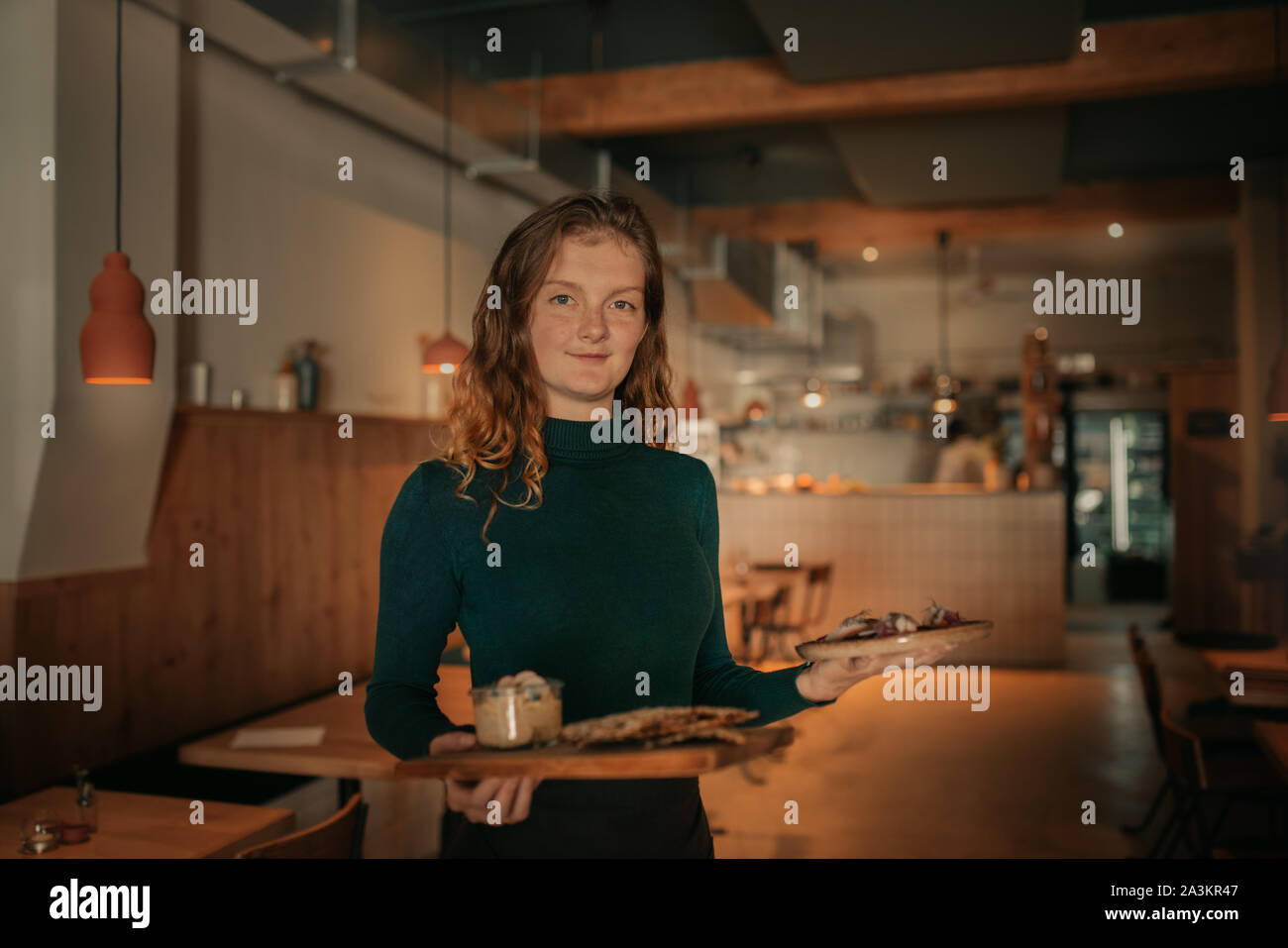 Waitress carrying orders of food in a bistro at night Stock Photo