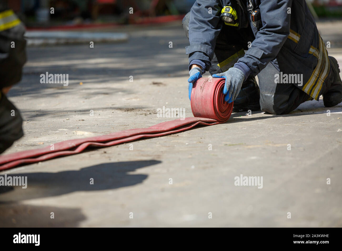 Fireman unwinding red fire hose outdoors in afternoon Stock Photo Alamy