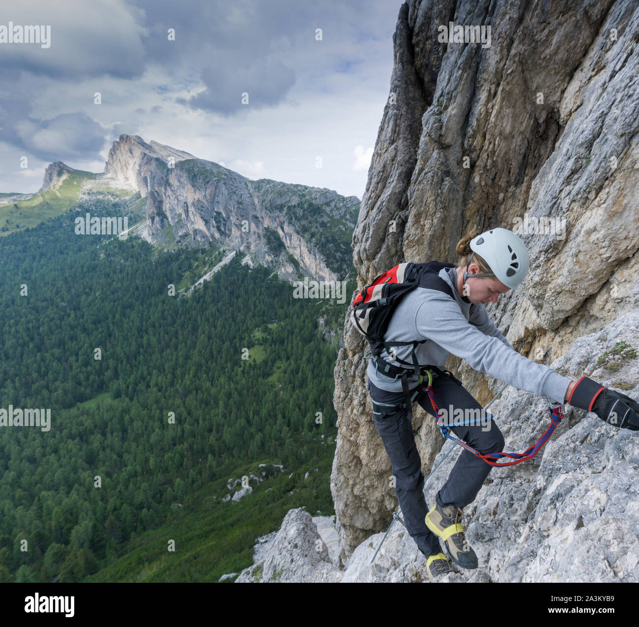 A young male climber on a Via Ferrata in the Dolomites of Alta Badia with damaged and broken shoes Stock Photo