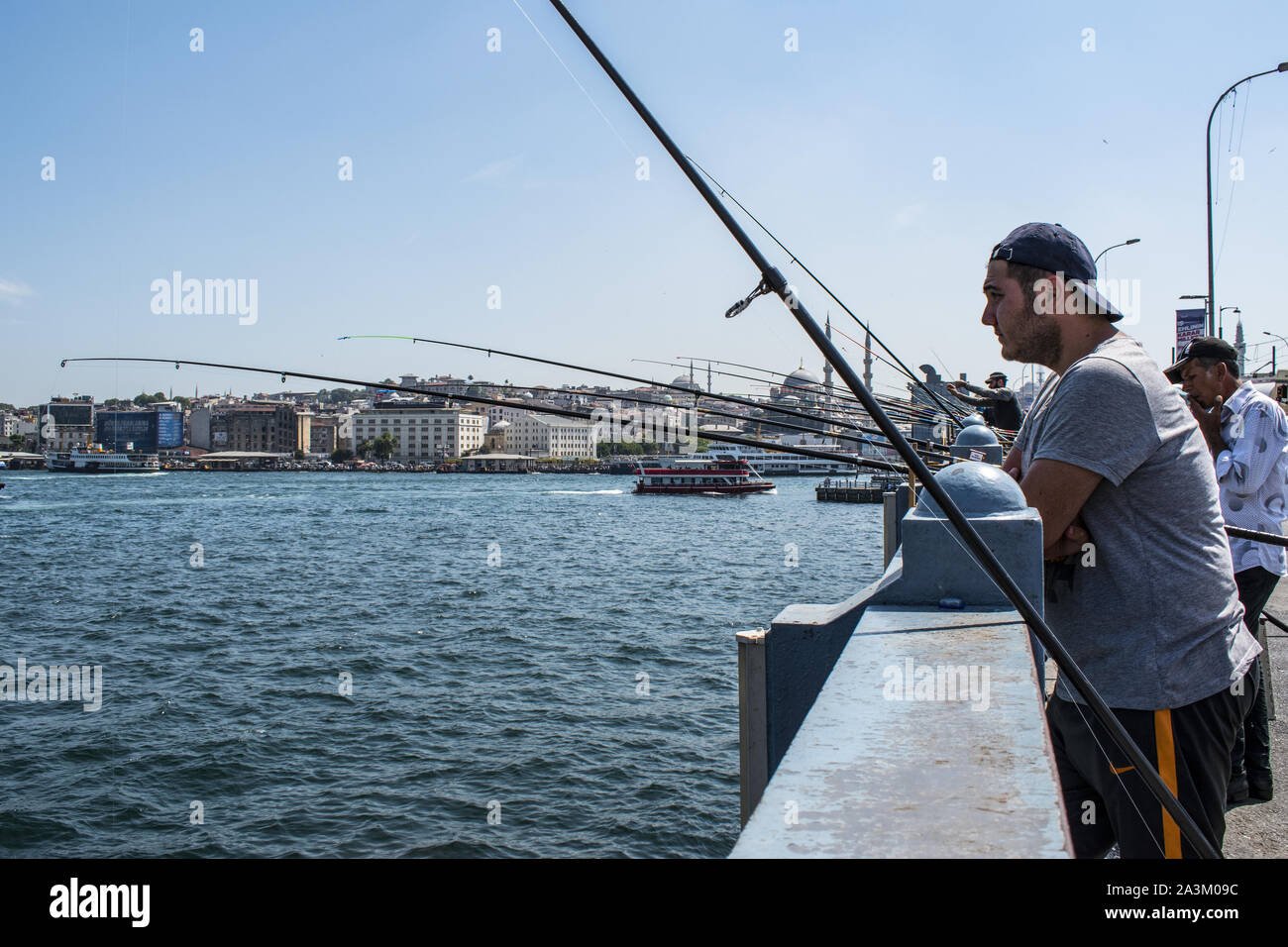 Istanbul: skyline of the city and local fishermen with their fishing rod on the Galata Bridge, the bridge spanning the Golden Horn and the Bosphorus Stock Photo