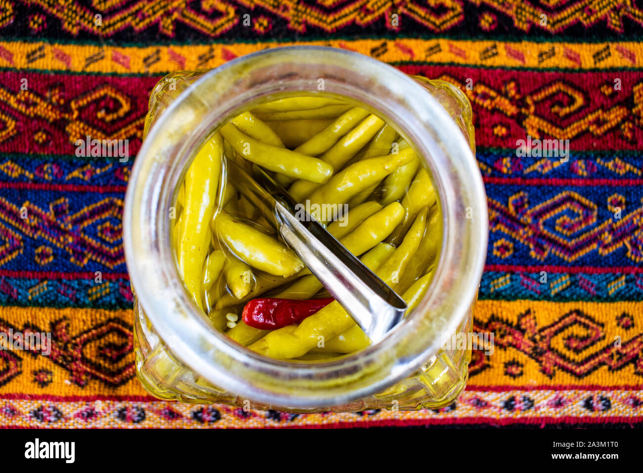Istanbul, Turkey: Middle Eastern food and lifestyle, a jar of spicy green chillies and hot pepper on a damask tablecloth Stock Photo