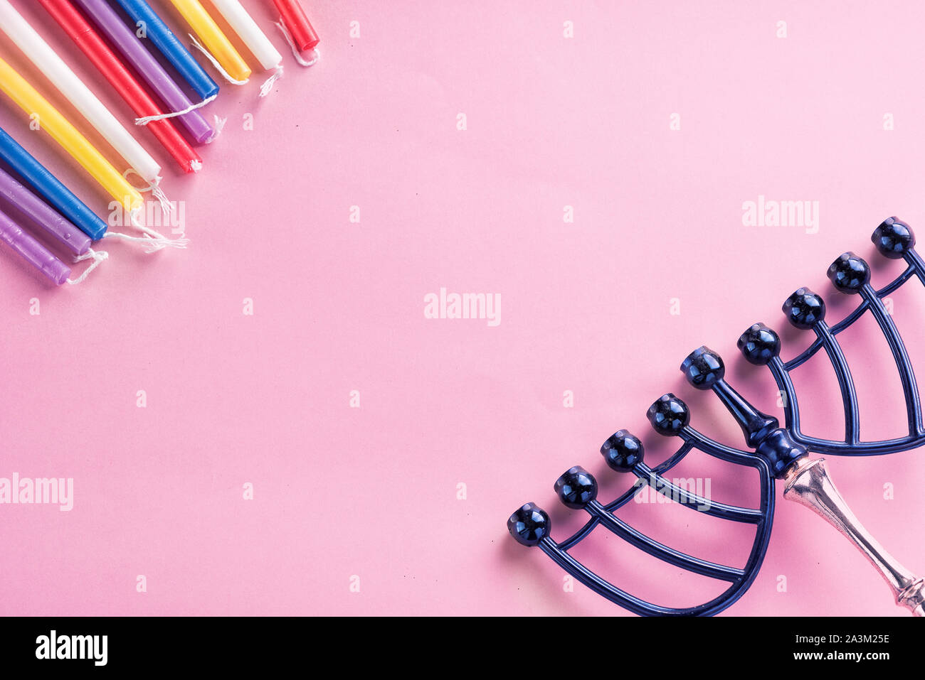 Image of jewish holiday Hanukkah colorful candles, menorah traditional Candelabra on pink background.Flat lay.Copy space for text. Stock Photo