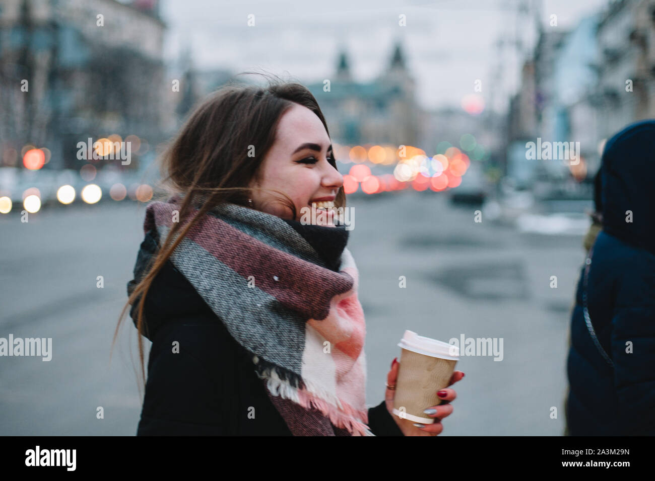 Happy woman in warm clothing crossing city street in winter Stock Photo
