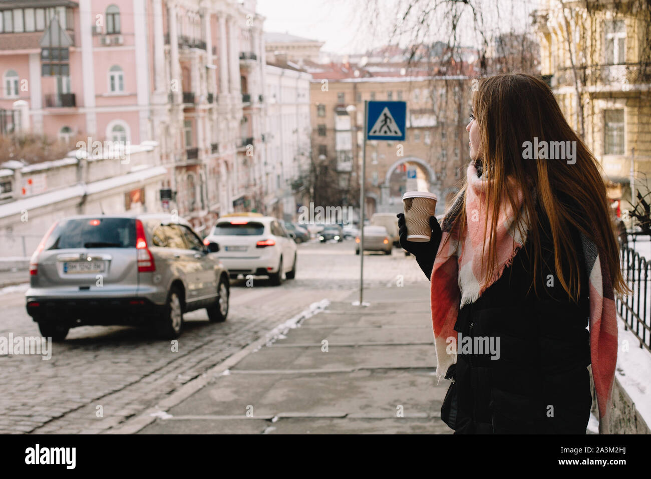 Woman with disposable cup in warm clothing standing in city street during winter Stock Photo