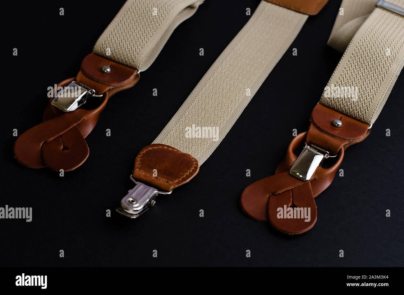 Close-up on Leather details of suspenders on black background. Men's accessories concept Stock Photo