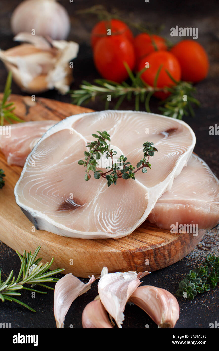 Two shark steak with vegetables and herbs on a dark board Stock Photo