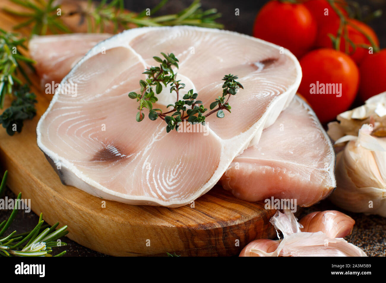 Two shark steak with vegetables and herbs on a dark board Stock Photo